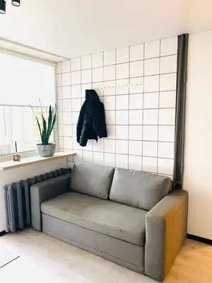 a couch sitting in a living room with a window at Modern & Cozy Gem - Spacious Central Retreat with private entrance in Vilnius