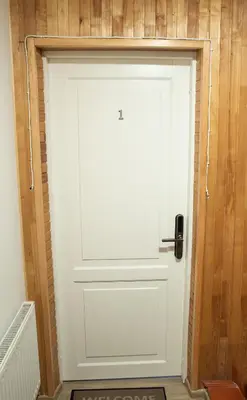 a white door in a room with a wooden wall at Svečių namai Aurėja in Kėdainiai