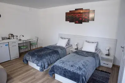two beds in a room with a kitchen and a desk at Svečių namai Aurėja in Kėdainiai