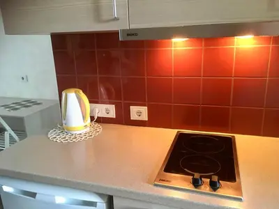 a kitchen counter with a stove and red tiles at Natalex MicroLofts in Vilnius