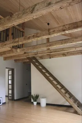 a loft with wooden beams and a staircase at Inovatorių slėnis/ Innovators' valley in Antalieptė
