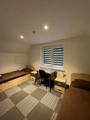 a bedroom with two beds and a desk and a window at Vaižganto Namas House for rent in Raseiniai