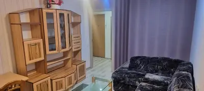 a living room with a cabinet and a chair at Cute Flat in Kėdainiai
