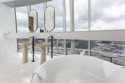 a bathroom with a white tub and mirrors at Vilnius TV Tower Apartments DEBESYS in Vilnius