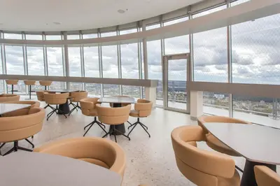 a restaurant with tables and chairs and large windows at Vilnius TV Tower Apartments DEBESYS in Vilnius