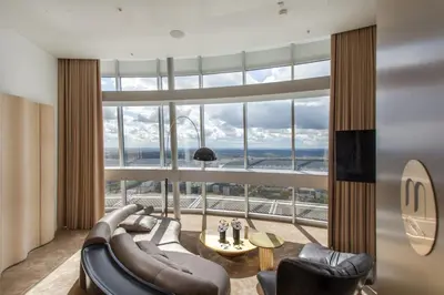 a living room with a couch and chairs and a large window at Vilnius TV Tower Apartments DEBESYS in Vilnius
