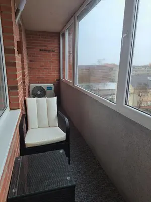 a chair and a table in a room with windows at Jaukūs apartamentai centre A. J. Greimo g. in Šiauliai