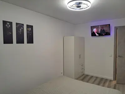a bedroom with a bed and a tv on the wall at Jaukūs apartamentai centre A. J. Greimo g. in Šiauliai