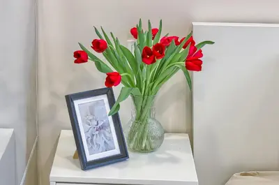 a vase filled with red flowers next to a picture at Business-class apartments 1 x Free parking x SELF CHECK IN 24x7 in Vilnius
