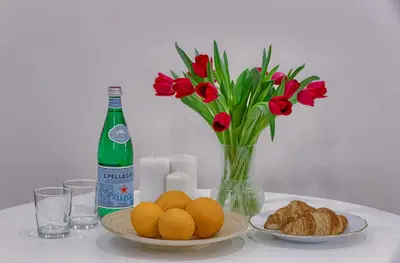 a table with plates of oranges and a bottle of wine and flowers at Business-class apartments 1 x Free parking x SELF CHECK IN 24x7 in Vilnius