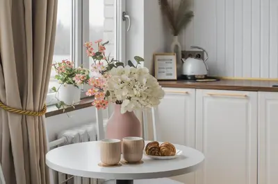 a vase with flowers on a table in a kitchen at Old Town view Apartment in city center in Anykščiai