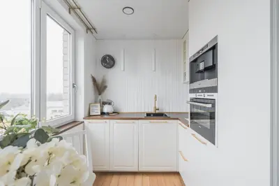 a kitchen with white cabinets and a large window at Old Town view Apartment in city center in Anykščiai