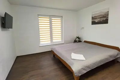 a white bedroom with a bed and a window at Pakalnės sodyba in Skverbai
