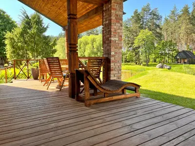 a wooden deck with two chairs and a gazebo at Pakalnės sodyba in Skverbai