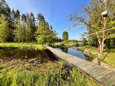 a wooden bridge over a pond in a park at Pakalnės sodyba in Skverbai