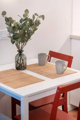 a table with two cups and a vase with flowers at Cozy studio in the city center in Vilnius