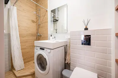 a bathroom with a washing machine and a sink at Cozy studio in the city center in Vilnius