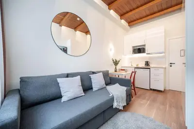 a living room with a blue couch and a kitchen at Cozy studio in the city center in Vilnius