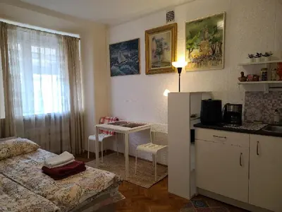 a bedroom with a bed and a table and a refrigerator at Tiny center G studio in Kaunas