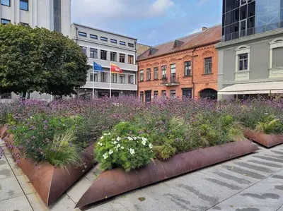 a garden with purple and white flowers and buildings at Tiny center G studio in Kaunas