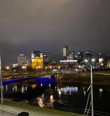 a city skyline at night with a river and a bridge at Cathedral Apartment FREE Parking in Vilnius