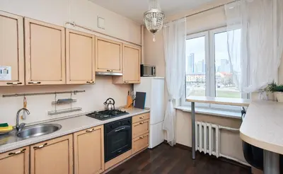 a kitchen with wooden cabinets and a sink and a window at Cathedral Apartment FREE Parking in Vilnius