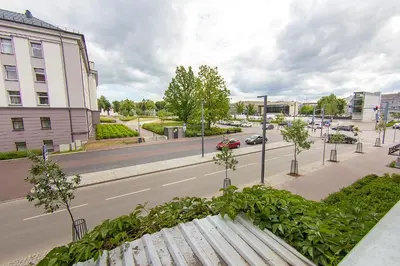 a view of a city street with a wooden bench at Butas Šiaulių mieste in Šiauliai