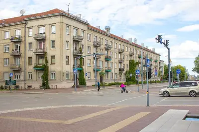 a city street with a building and a car on the street at Butas Šiaulių mieste in Šiauliai