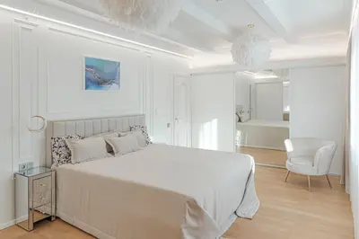a white bedroom with a large bed and a chair at 252 m² luxury 4 bedroom house in the pine-forest in Vilnius