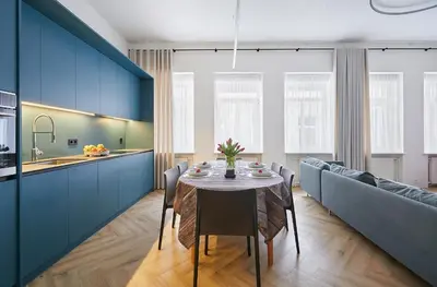 a kitchen and dining room with blue cabinets and a table at Kurpiai Old Town, 3BD in Kaunas