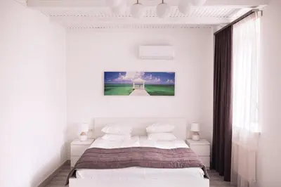 a white bedroom with a bed and a window at Laurentroom Hotel in Ukmergė