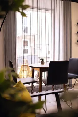 a living room with a table and chairs and a large window at Laurentroom Hotel in Ukmergė