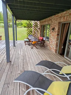 a wooden deck with chairs and a grill on it at Forest apartment in the loop of the river Neris in Verkšonys