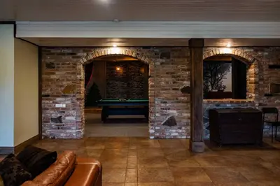 a living room with a pool table in a brick wall at Forest apartment in the loop of the river Neris in Verkšonys