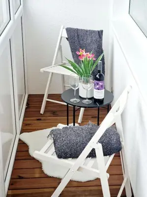 a table with a vase of flowers and a chair at City Center Apartment with balcony in Anykščiai