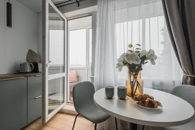 a white dining room table with a vase of flowers at City Center Apartment with balcony in Anykščiai