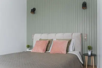 a white bed with two pink pillows on it at City Center Apartment with balcony in Anykščiai