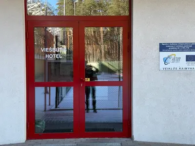 a red door to a hotel with a person standing inside at Alytaus sporto viešbutis Self Check-in in Alytus