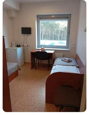 a room with two beds and a desk and a window at Alytaus sporto viešbutis Self Check-in in Alytus