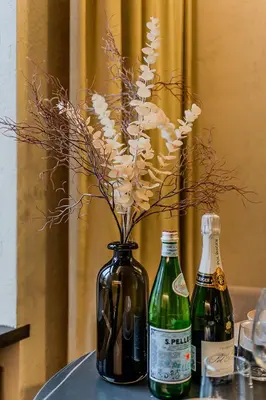 a vase with flowers in it on a table with two bottles at Central Park Apartments - The Luxury Collection in Kaunas