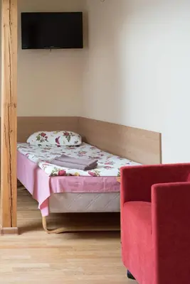 a small bedroom with a bed and a red chair at Kaimo turizmas 