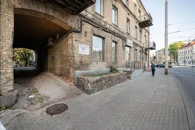 a person walking down a sidewalk next to a brick building at Warm studio in the heart of city in Vilnius
