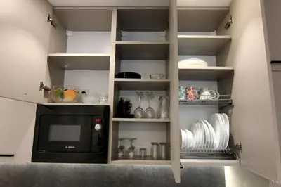 a kitchen with white shelves and a microwave at Warmzy Home - Modern 2 Rooms Apartment With Free Parking in Vilnius