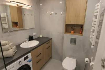 a bathroom with a toilet sink and a washing machine at Warmzy Home - Modern 2 Rooms Apartment With Free Parking in Vilnius