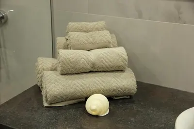 a stack of towels sitting on a counter in a bathroom at Warmzy Home - Modern 2 Rooms Apartment With Free Parking in Vilnius