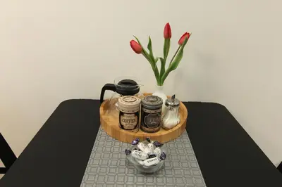 a table with a tray with jars and a vase of flowers at Warmzy Home - Modern 2 Rooms Apartment With Free Parking in Vilnius