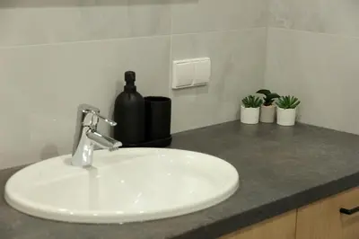 a bathroom counter with a sink and a bottle of wine at Warmzy Home - Modern 2 Rooms Apartment With Free Parking in Vilnius