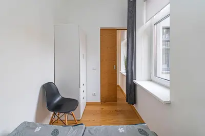 a black chair in a bedroom with a window at CityVibe apartment by Polo Apartments in Kaunas