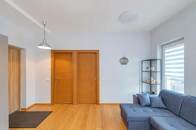 a living room with a blue couch and a wooden door at UrbanLife Apartment by Polo Apartments in Kaunas