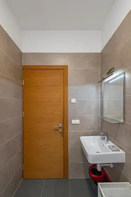 a bathroom with a sink and a wooden door at UrbanLife Apartment by Polo Apartments in Kaunas